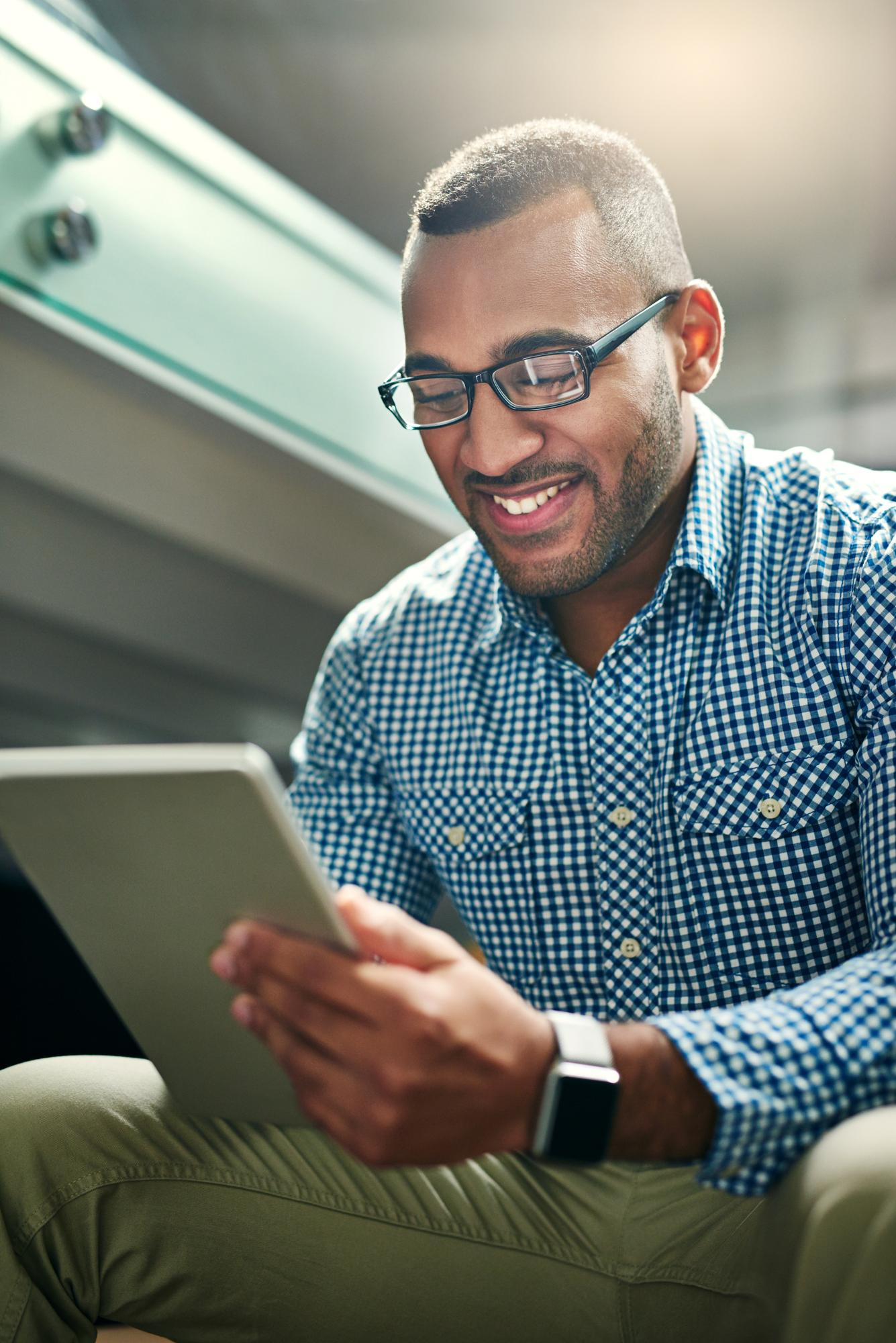 Homem sorrindo enquanto acompanha publicações em um tablet
